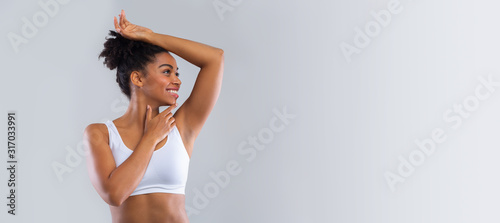 Cheerful black girl smelling her armpit over grey background photo