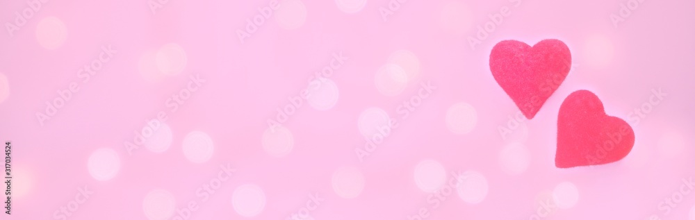 Two red hearts on a light pink blurry background with bokeh. Valentines Day greeting card. The concept of love, romance. Holiday banner, copy space for text.
