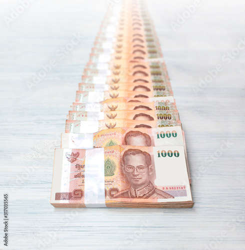 Slika na platnu Wad of Thai banknotes tiled to behind on white wooden background