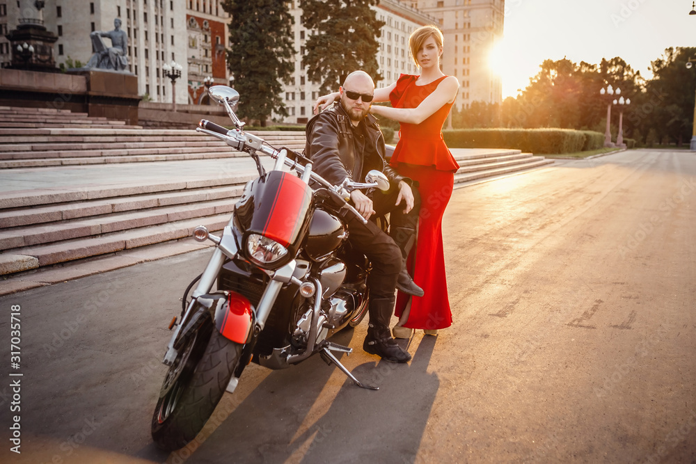 Fototapeta premium Beautiful unusual couple on a motorcycle against the of Moscow State University.