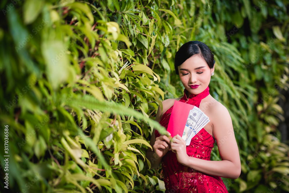Happy Chinese girls in Chinese dress traditional Cheongsam, showing red envelopes on hands. Happy Chinese New Year