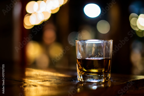 a glass of whiskey on wood bar, soft focus. 