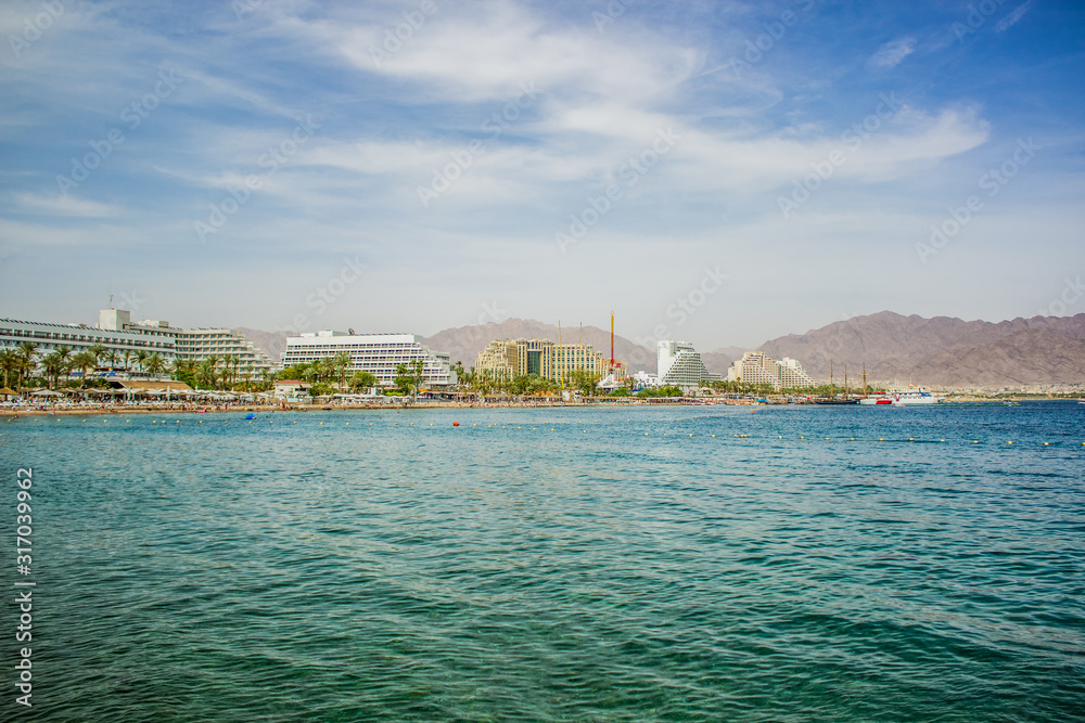summer time vacation season destination Middle East Israeli city Eilat on Red sea bay Gulf of Aqaba port hotel district waterfront side with water foreground, copy space for your text