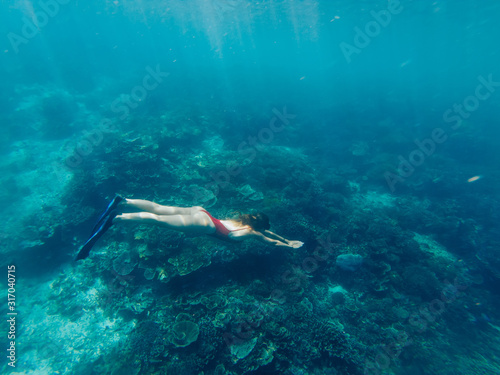Woman exploring world during extreme adventure journey diving in ocean for swimming near coral tropical reefs, female snorkeling in flipper discover aquatic life in Bali during leisure time