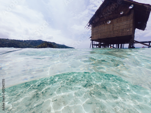 Landscape view of tropical island with bungalow for recreating during summer vacations on exotic Raja Ampat in New Guinea  seascape view of picturesque nature environment with scenic waterline