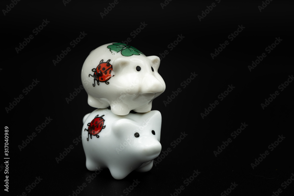 Two small white porcelain piggies, black background Two small white porcelain piggies, black background