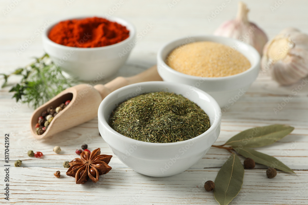 Bowls with different spices and ingredients on wooden background, close up