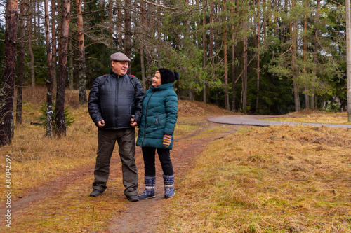 Elderly men and a woman walk along a forest path together.