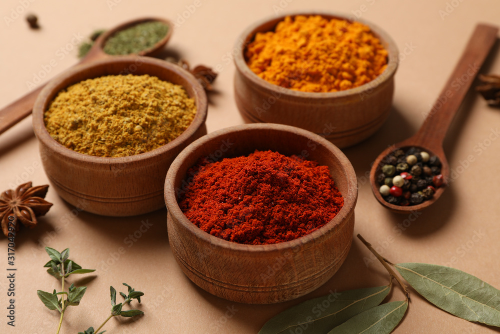 Spoons and bowls with different powder spices on craft background, close up