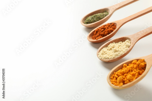 Spoons with different powder spices on white background, space for text