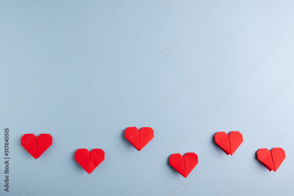 Love day. Handmade DIY red origami hearts on a blue background. Top view.