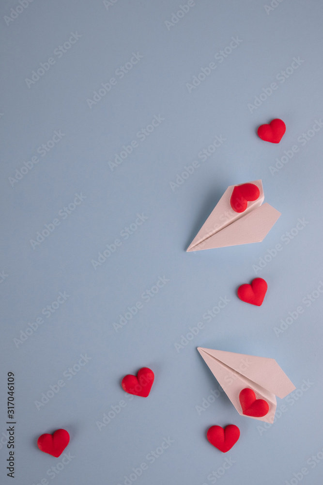 Valentine's Day background. Red candy  hearts and paper plane on pastel blue background. Valentines day concept. Flat lay, top view, copy space