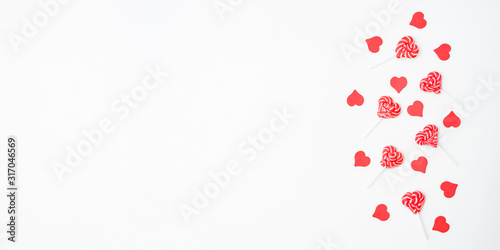 Flat lay valentines day border with red hearts and sweets on a white background
