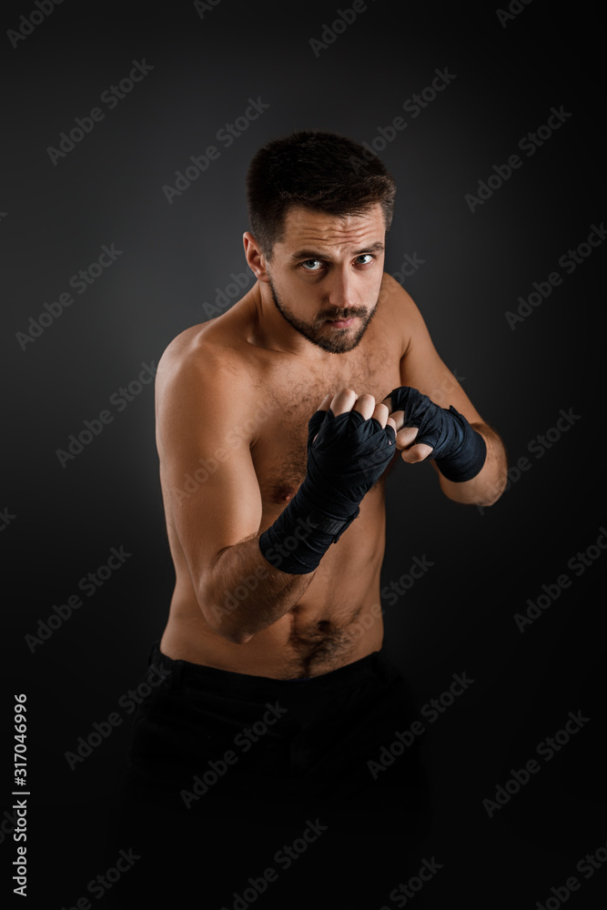 boxer man with bandage on hands training before fight and showing the different movements on black background