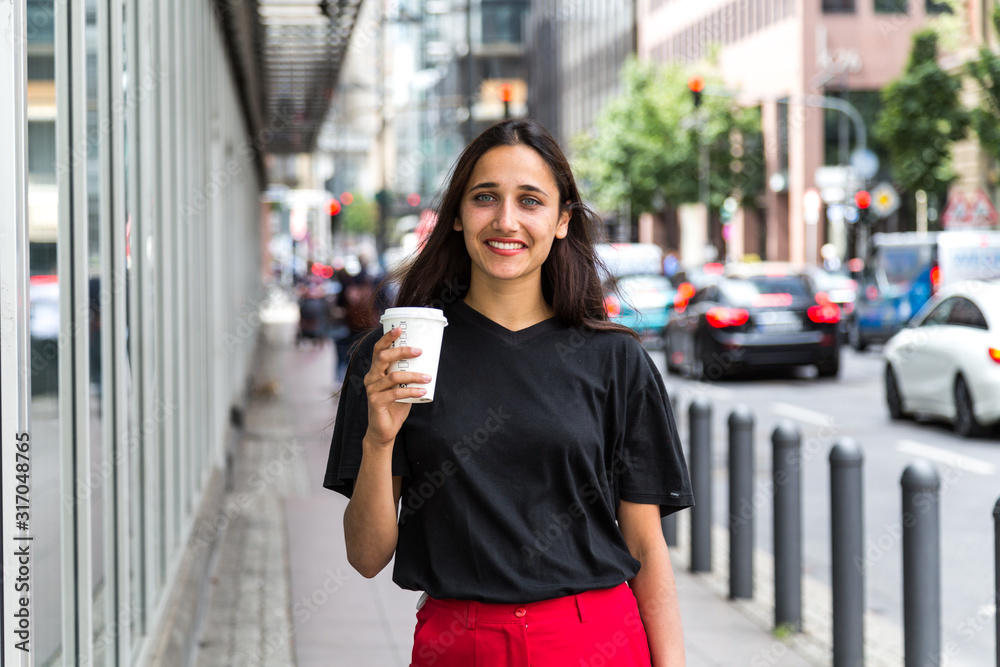 Obraz premium Indian Ethnicity Woman Holding Paper Cup and Smiling in Urban Setting