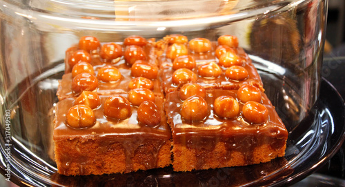 Hazelnut cake on a plate with glass cover on a shelf in cake shop