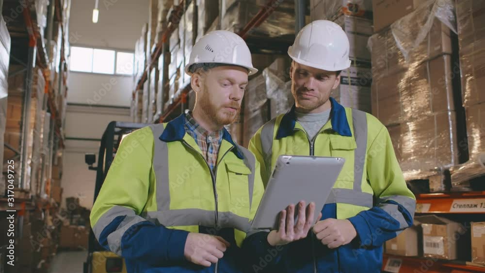 Workers in warehouse controlling incoming merchandise using digital tablet