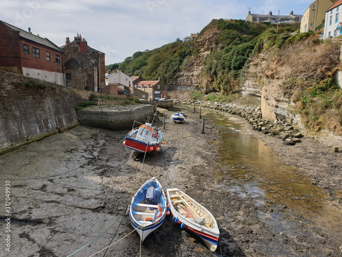 Fishing villageat low tide with boats, old harbour buildings and clifftop houses  photo