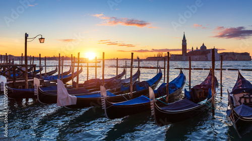 Venice with famous gondolas at sunrise, Italy. Gondolas in lagoon of Venice on sunrise, Italy. Venice with gondolas on Grand Canal against San Giorgio Maggiore church. © daliu