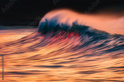 wave with spray breaking at sunset with in camera panning technique © mimadeo