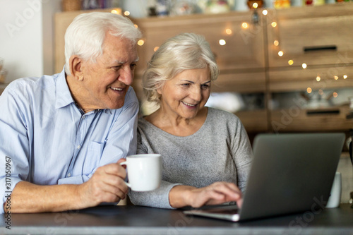Senior couple using laptop in their kitchen