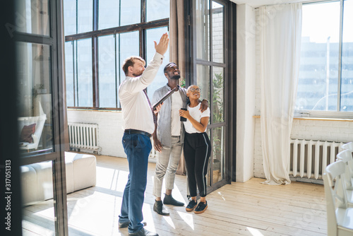 фотографія Professional estate agent showing apartment to African American amused couple