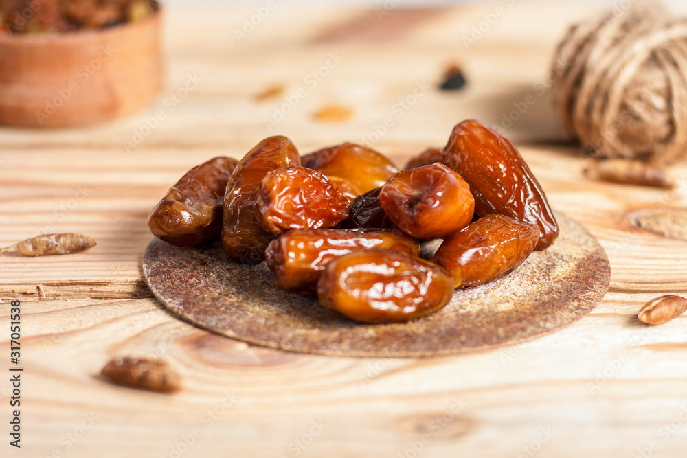 Tasty dates on a round substrate close-up on a wooden background Tasty dates on a round substrate close-up on a wooden background