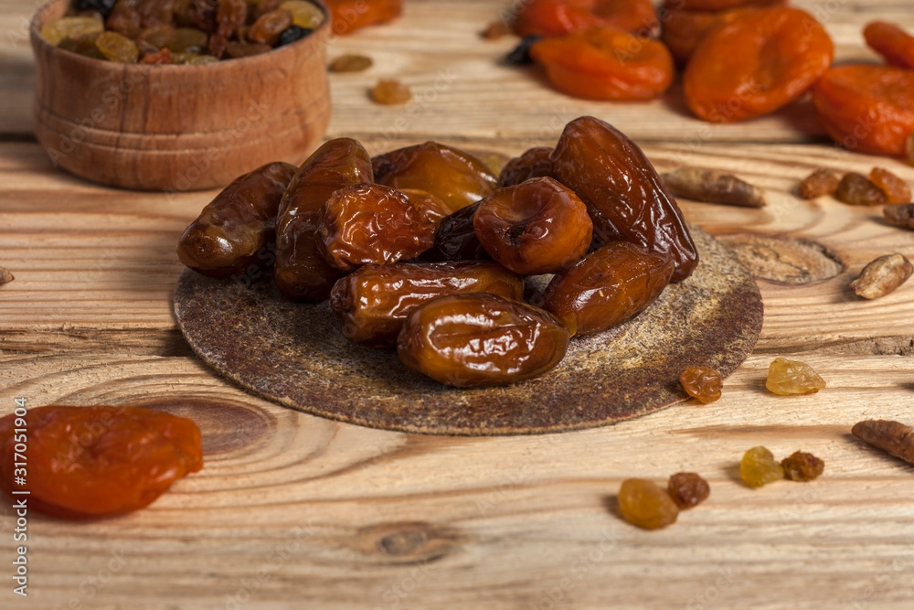 Tasty dates on a round substrate close-up on a wooden background Tasty dates on a round substrate close-up on a wooden background