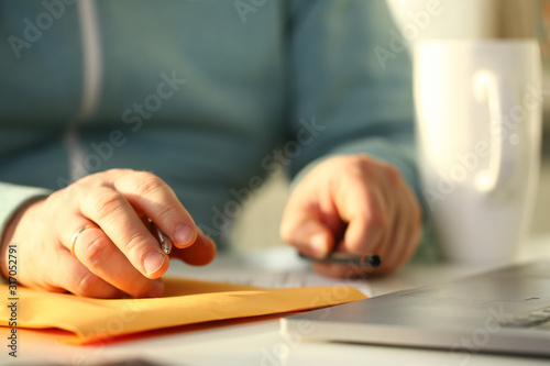 Male hand holding silver pen. Fill in address on yellow envelope of mail correspondence for application hiring concept