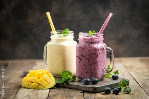 Delicious blueberry and mango smoothie in mason jar on a rustic background. Healthy food, detox diet. Copy space..