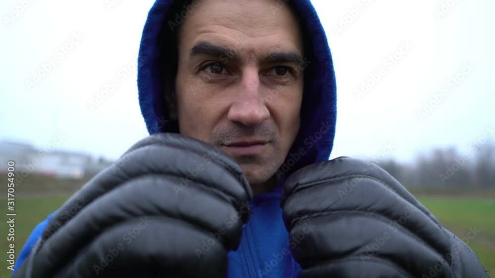 man boxer wearing boxing gloves, anger problem, man in a hood looking aggressive, trying to provoke someone for fight, anger managment, conflict box, training zoom in man boxer wearing boxing gloves, anger problem, man in a hood looking aggressive, trying to provoke someone for fight, anger managment, conflict box, training zoom in