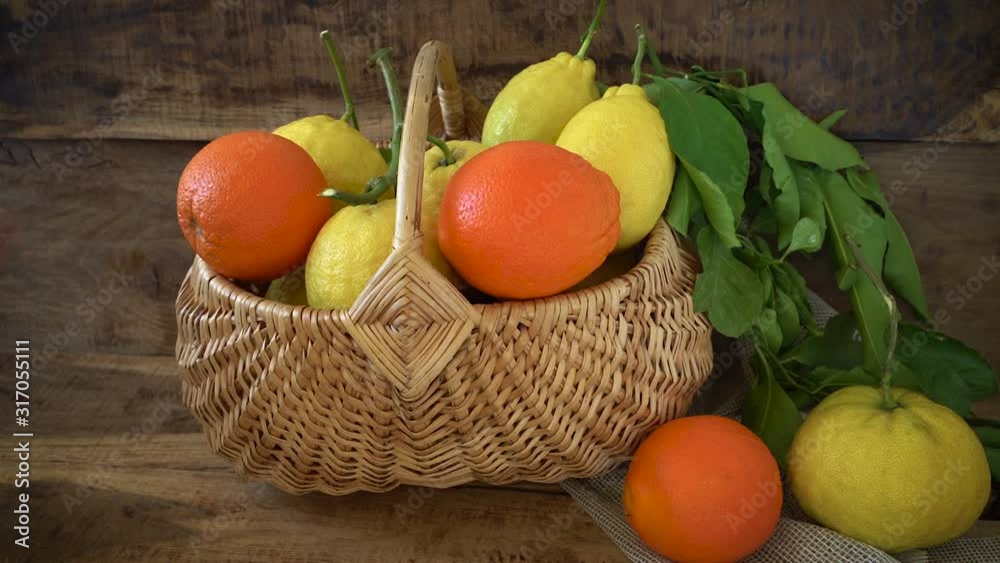 Children's hands take oranges, tangerines from a basket on a wooden background
