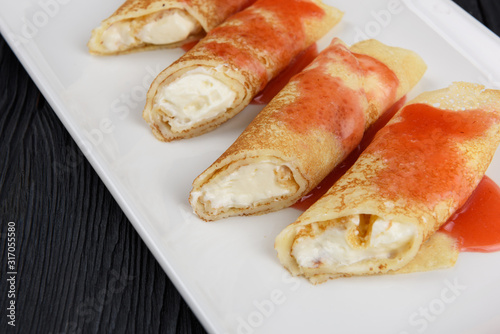 Pancakes or russian blini stuffed with cream sauce on a white plate.