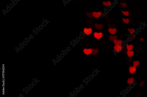 Abstract beautiful romantic picture of blur brightness red colored of swirling heart shaped bokeh on black from ornamental lights flickering. Background for Valentine’s day or Love or Romance concept.