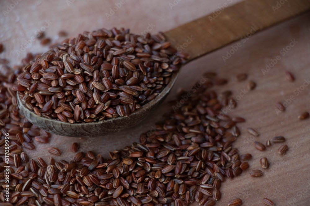 Obraz premium Wild rice, red and brown rice. on a wooden board. Wooden spoon on a white background. Healthy food, breakfast.