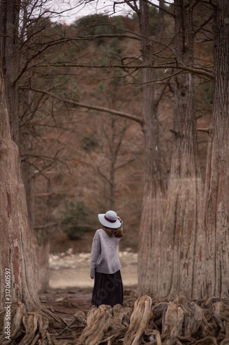 girl in a hat in the middle of cypress trees