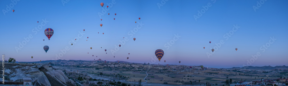 Cappadocia, Turkey, Europe: hot air balloons floating at dawn and view of the valley around Cavusin, town of the historical region in Central Anatolia rich of exceptional natural wonders