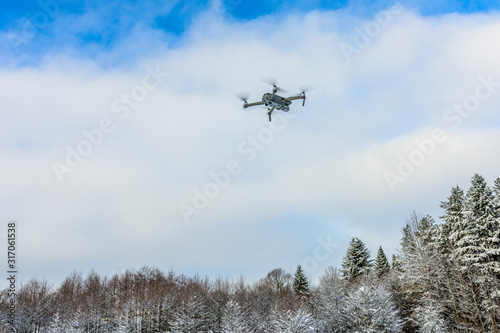 The drone flies in the winter above the forest and shoots landscape videos.
