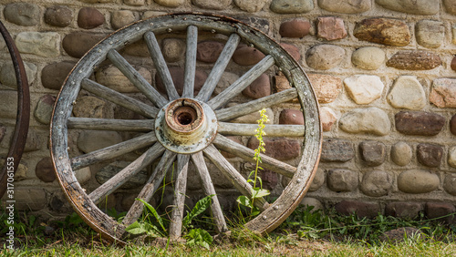 Old cartwheel by the stone wall of an old building photo