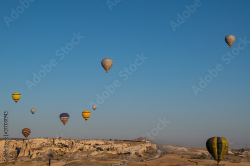 Cappadocia, Turkey, Europe: traditional hot air balloons floating after dawn in the sky over the valley of Cavusin in the historical region in Central Anatolia rich of exceptional natural wonders