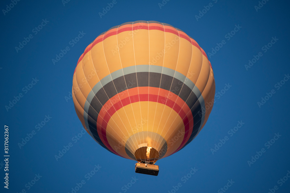 Naklejka premium Cappadocia, Turkey, Europe: a traditional hot air balloon floating after dawn in the sky over the valley of Cavusin in the historical region in Central Anatolia rich of exceptional natural wonders