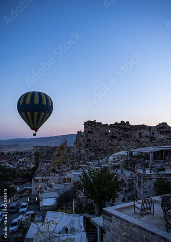 Cappadocia, Turkey: a hot air balloon floating at dawn on the church of St. John the Baptist (Cavusin castle), famous 5th century cave church on top of the hill of the old town of Cavusin 