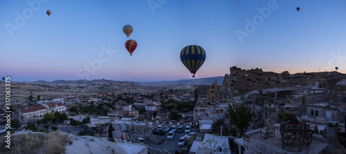 Cappadocia, Turkey: hot air balloons floating at dawn on the church of St. John the Baptist (Cavusin castle), famous 5th century cave church on top of the hill of the old town of Cavusin 