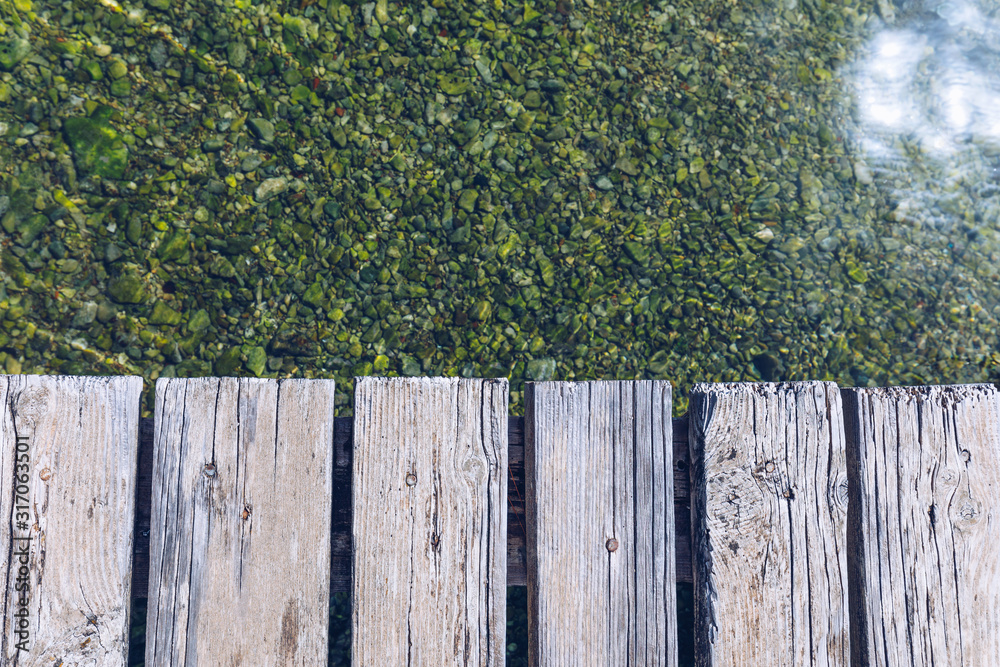 Wooden board empty over sea, can be used for display or present a product. Summer season. Empty perspective wooden planks over the reflection of green water, product display template.