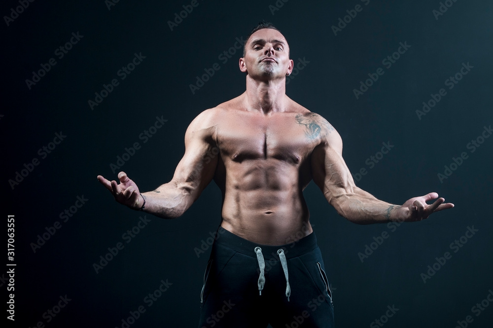 Male bodybuilder with an athletic build on a dark background. athlete, exercise, health, power, strength, man,