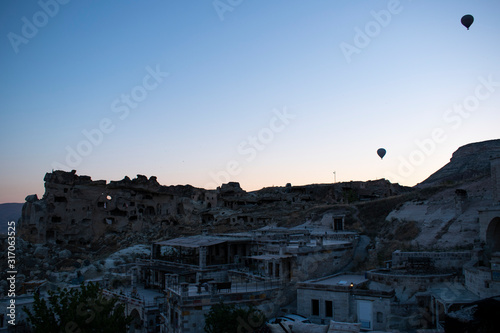 Cappadocia, Turkey: hot air balloons floating at dawn on the church of St. John the Baptist (Cavusin castle), famous 5th century cave church on top of the hill of the old town of Cavusin 