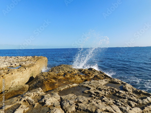 sea waves hitting the rocky shore on the beach of Malta photo