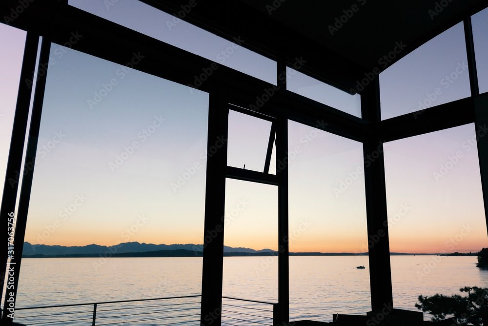 Luxury home windows with view of sunset over mountains and water. 