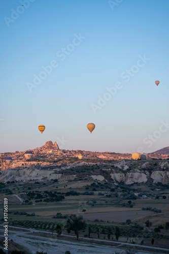 Cappadocia, Turkey: aerial view of Uchisar, ancient town of the historical region in Central Anatolia rich of exceptional natural wonders, with hot air balloons floating in the pink sky at dawn 