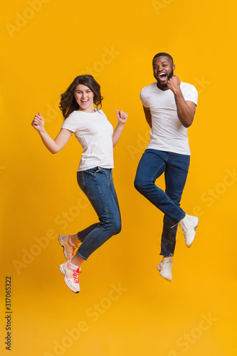 Joyful interracial couple jumping in air and shouting with excitement